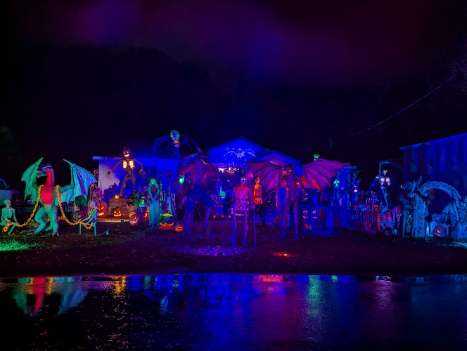 Night shot of a house with many light up Halloween figure decorations